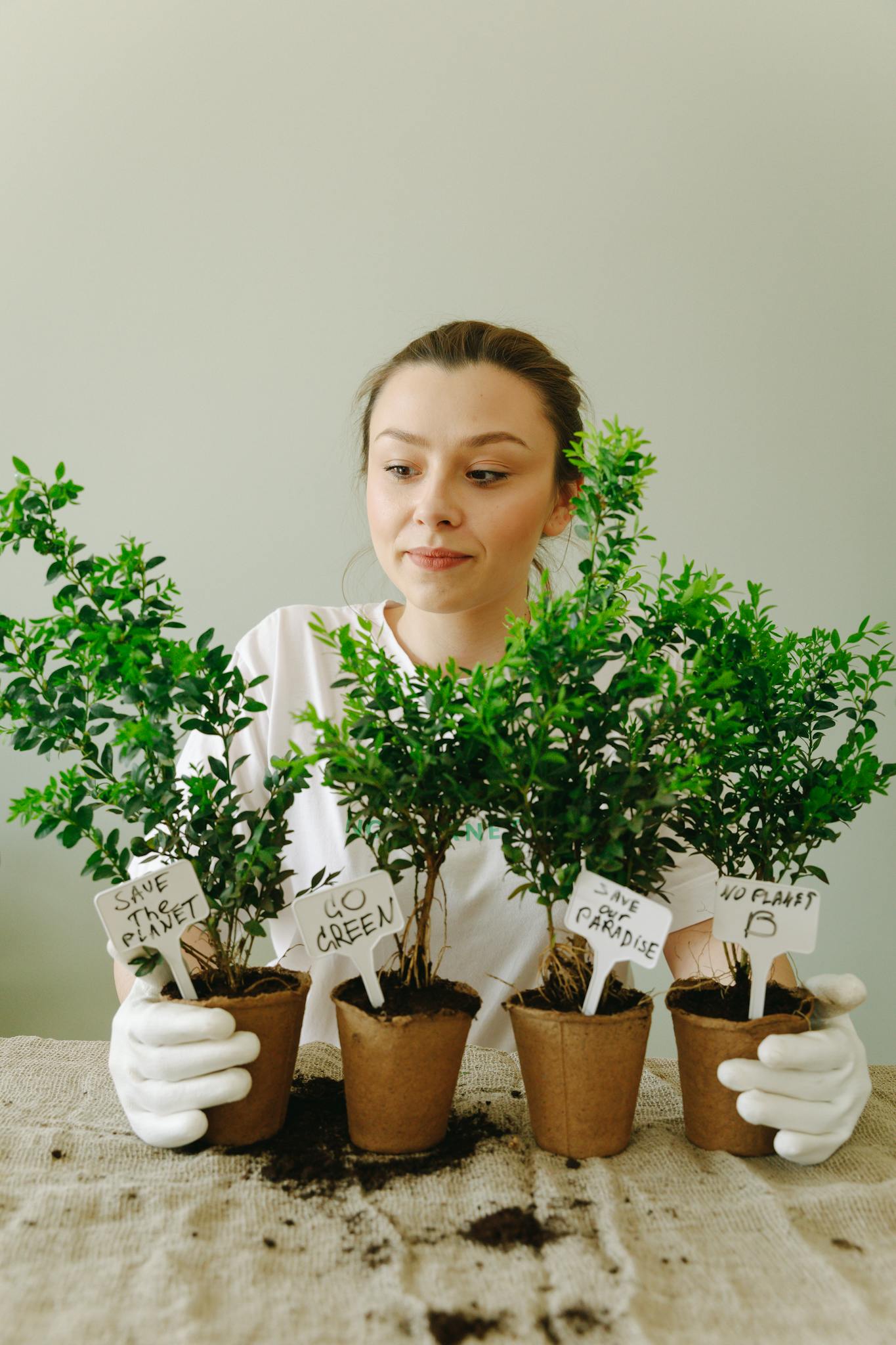 Young woman caring for potted plants indoors, promoting eco-friendly practices and sustainability.